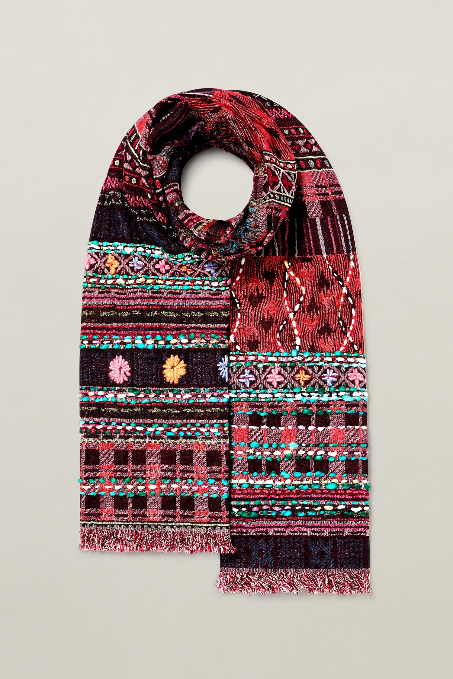 The Hand Embroidered Cotton Scarf, featuring a multicolored palette with intricate geometric and floral designs in hues of red, black, green, and blue, is neatly folded against a plain background. Truly versatile and stylish.