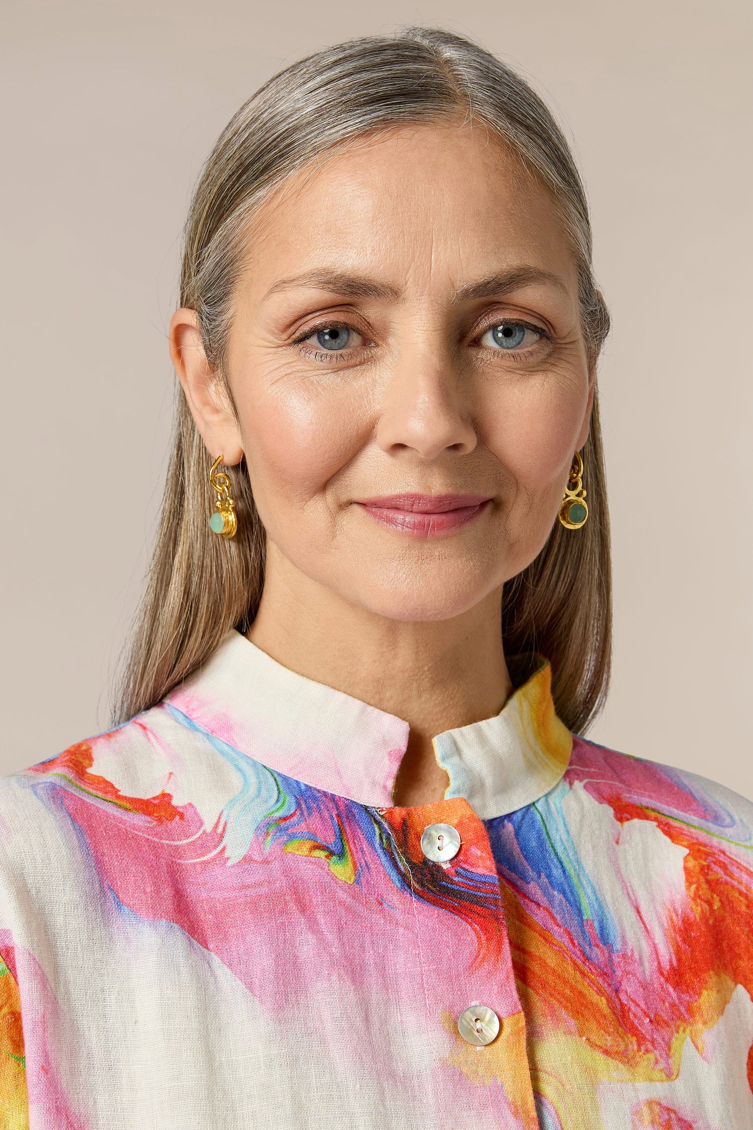 A woman wearing Handcrafted Aquamarine Drop Earrings and a colorful shirt.