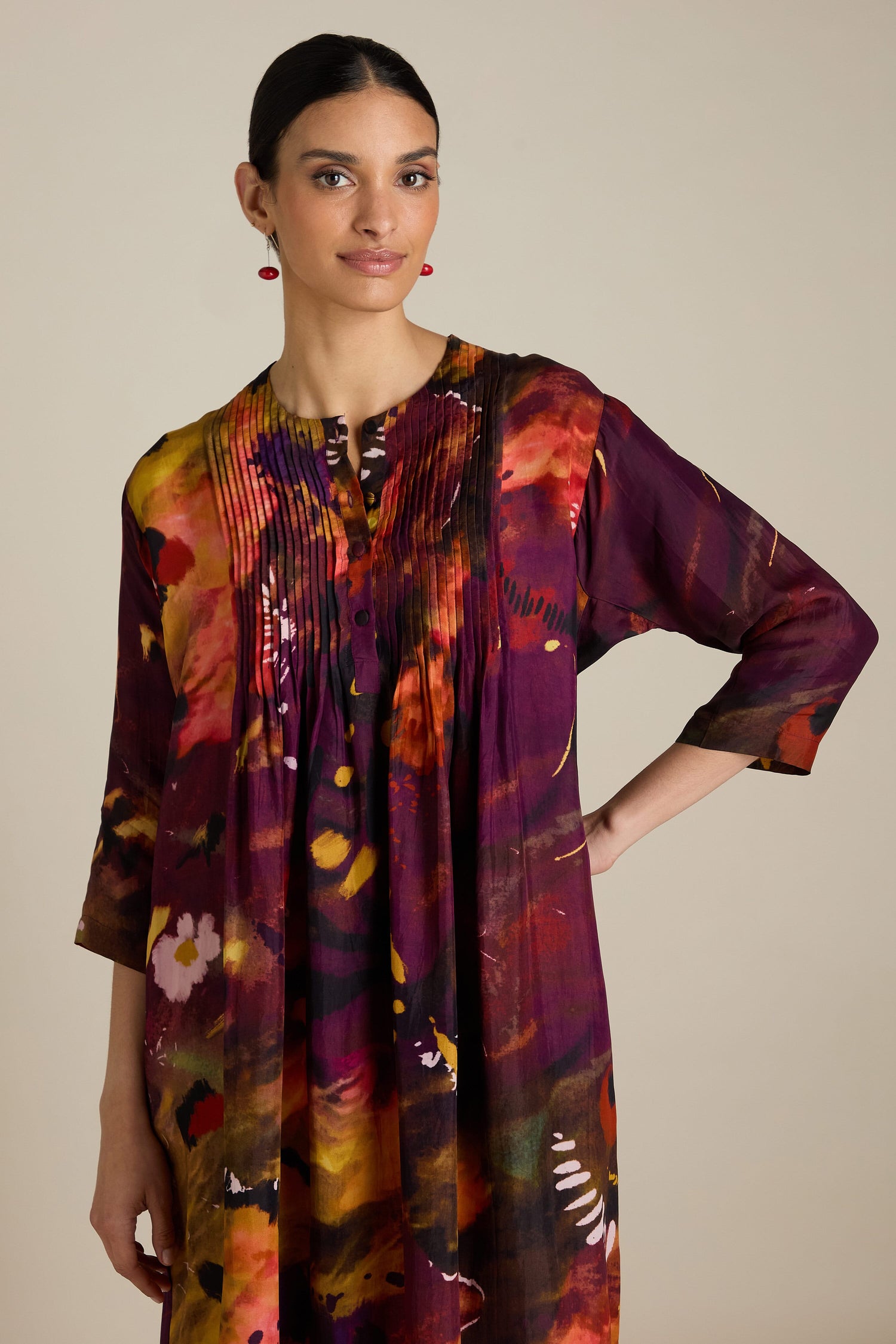 Woman wearing an Abstract Flower Pleated Dress with 3/4 length sleeves, standing against a neutral background, reminiscent of impressionist art.