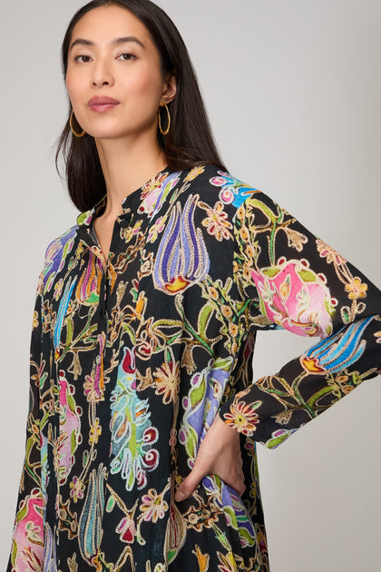 A woman in the Protea Flower Dress—featuring long sleeves and vibrant floral embroidery—demonstrates how fashion as art can turn any outfit into a bold statement piece.